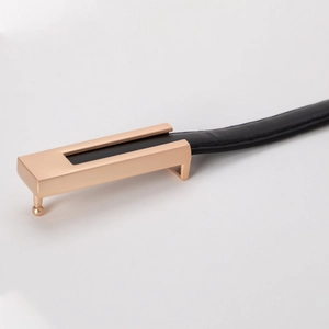Détail d'une ceinture fine en cuir noir avec une boucle rectangulaire polie en or rose brillant