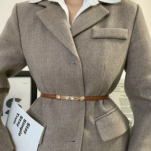 Dettaglio cintura sottile in pelle marrone con fibbia di perle su blazer di lana