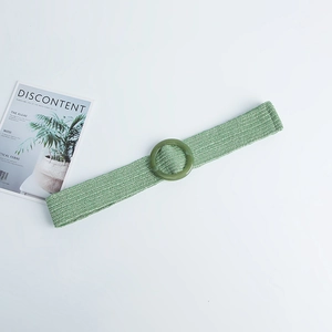 Close-up of light green woven straw waist belt with a matching round resin buckle detail