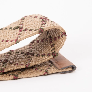 Détail de ceinture tressée ethnique avec broderie rouge-verte et bout en cuir