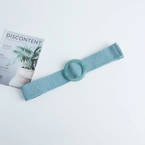 Detail of light green bohemian woven elastic waist belt with a round resin buckle