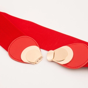 Gros plan d'une ceinture élastique rouge avec boucle en métal doré et détails en similicuir