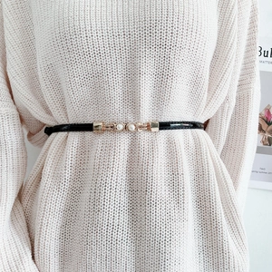 Fine ceinture élégante en cuir verni noir avec boucle perle dorée sur robe tricotée