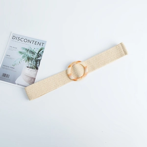 Detailed macro view of beige straw woven belt with round amber-textured resin buckle
