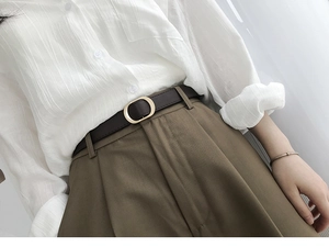 Gros plan d'une fine ceinture en cuir marron foncé avec boucle dorée ovale