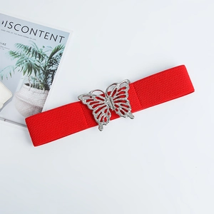 Détail d'une ceinture élastique rouge avec boucle papillon argentée et strass