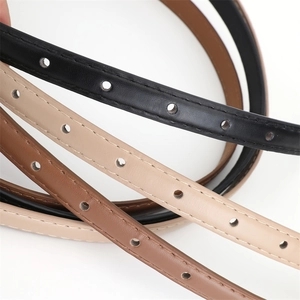 Gros plan de ceintures fines en cuir noir, beige et marron avec détails de couture