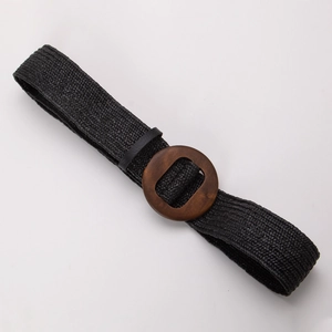 Détail de la texture d'une ceinture tressée noire avec boucle ronde en bois