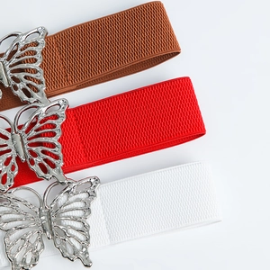 Détail des boucles papillon sur les ceintures élastiques en couleurs marron, rouge et blanc