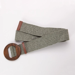 Détail d'une ceinture tressée en paille verte avec une boucle ronde en bois