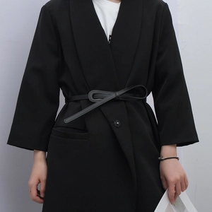 Detail showing a thin black leather belt knotted on a tailored suit jacket for women