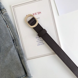 Détail d'une ceinture marron foncé minimaliste avec une boucle ovale en métal doré