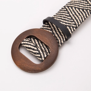 Détail d'une ceinture tressée bohème avec boucle ronde en bois et motif à chevrons