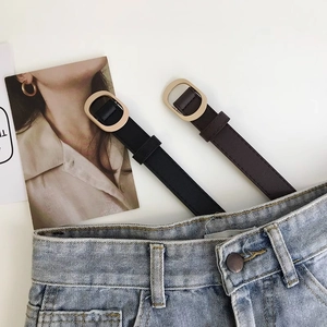 Ceintures fines pour femmes en noir et marron avec boucle ovale dorée sur un jean denim
