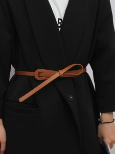 Close-up of brown knotted leather belt styled on a black blazer for elegant waist decoration