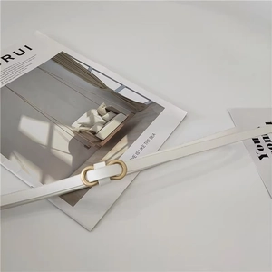 Detailed view of white thin PU leather belt with a golden figure-eight metal buckle