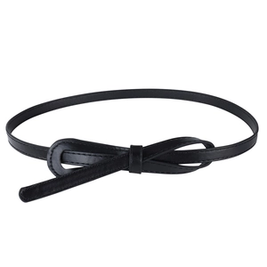 Detail of a thin black leather waist belt featuring an elegant fixed bow knot and ring buckle