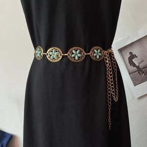 Detail der Vintage-Boho-Taillenkette mit türkisfarbenen Blumen auf schwarzem Kleid