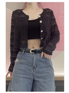 Detail of a thin black leather belt with a round metal buckle on light blue washed jeans