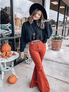 Détail de la chaîne de taille vintage en métal sur un pull noir et un pantalon orange