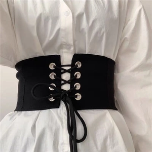 Dettaglio del corsetto nero con lacci e occhielli metallici su una camicia bianca
