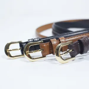 Close-up of thin leather belts in black and brown with polished gold horseshoe buckles