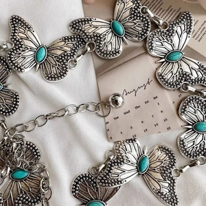 Bohemian silver butterfly waist chain with turquoise inlay on white fabric background