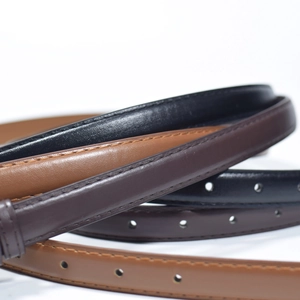 Macro detail of slim leather belts in black and brown with fine stitching and textures