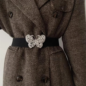 Ceinture noire élastique avec boucle papillon sertie de strass sur un manteau de laine