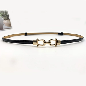 Detail of slim black leather belt featuring a gold-toned horseshoe interlocking buckle