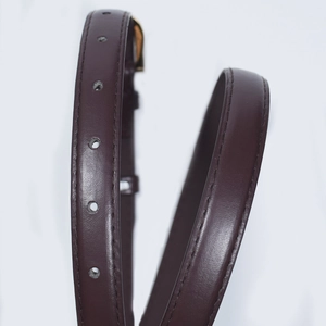 Macro view of vintage dark brown slim leather belt with gold buckle and stitching detail