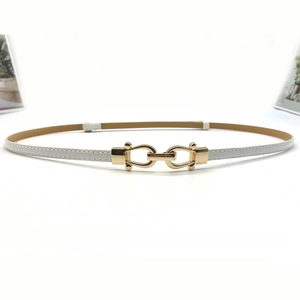 Detailed close-up of a white leather skinny belt featuring a golden horseshoe buckle