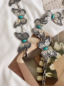 Close-up of butterfly waist chain with turquoise inlay and silver metal texture