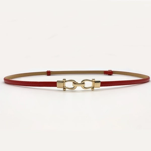 Close-up of a slim red leather belt with interlocking gold horseshoe metal buckle