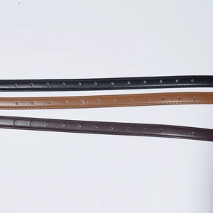 Detail of slim leather belts in black, brown and purple with silver metal eyelets