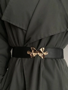 Detail of a black leather belt with a unique gold irregular-shaped metal buckle for women