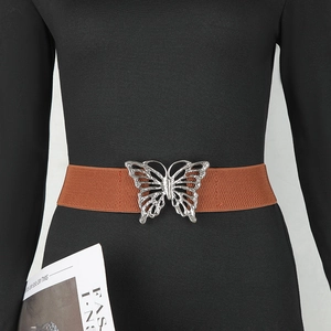 Détail de la boucle papillon argentée sur une ceinture élastique marron pour robe