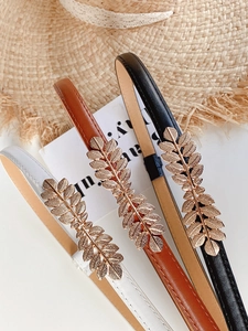 Detailed view of three slim belts with elegant golden leaf buckles in white, brown, and black