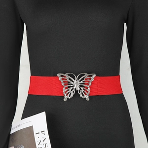 Détail d'une ceinture élastique rouge avec boucle papillon argentée et strass brillants