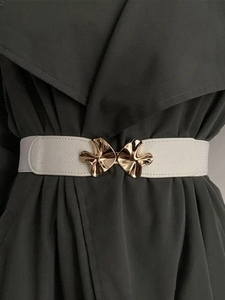 Macro shot of gold mushroom buckle and off-white lychee texture belt on green coat