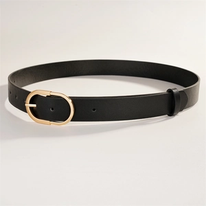 Détail d'une ceinture en cuir noir avec boucle ardillon ovale dorée polie et texture fine