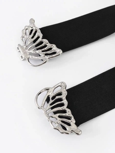 Détail d'une boucle papillon argentée sur une ceinture élastique noire pour robe