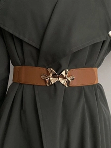 Close-up of brown elastic waist belt with an abstract gold leaf buckle on a trench coat