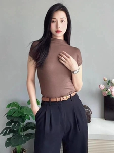 Fine ceinture marron avec boucle en métal sur un pantalon noir à taille haute
