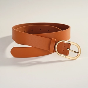 Détail d'une ceinture en cuir tan avec une boucle dorée ovale et des trous réglables