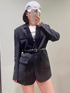 Détail d'une fine ceinture en cuir noir avec boucle dorée sur un blazer de costume noir