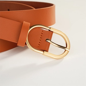 Détail d'une ceinture en cuir marron avec surface texturée et boucle ovale en métal doré