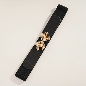 Macro detail of elastic black waist belt featuring a luxury gold wavy metal buckle