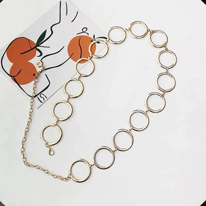 Detailed macro view of a golden metal waist chain featuring large round rings and adjustable clasp