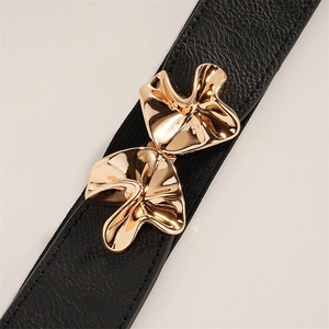 Detailed close-up of wavy gold metal buckle on black elastic waist belt for women